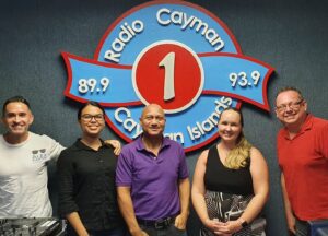 Four people standing in front of a radio cayman sign.