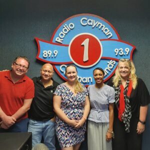 A group of people near Radio Cayman sign board