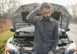 Man looking at broken down car.