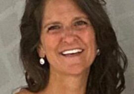 Smiling woman with dark hair and earrings.